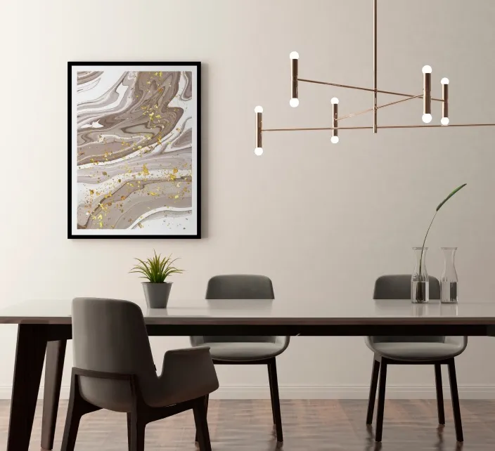 A dining table with gray upholstered chairs beneath a linear pendant light, with a framed marble-print artwork on the wall.