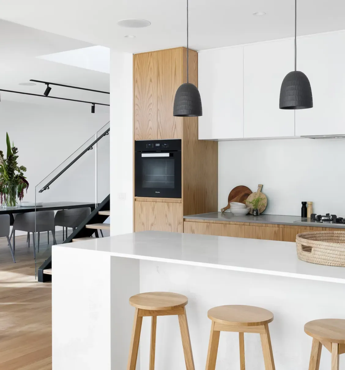A bright kitchen with wooden bar stools at a white island